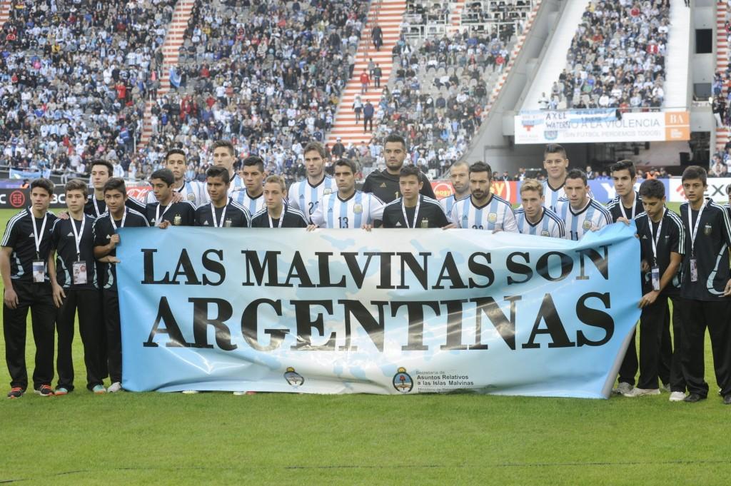 Jogadores argentinos posam para foto com banner reiterando posse das Ilhas Malvinas pelo país