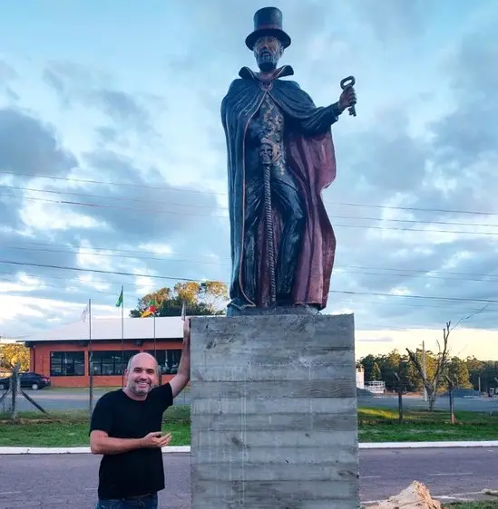 Mestre Lukas ao lado do monumento de Exú, também erguido em Gravataí | Foto: Reprodução/Facebook