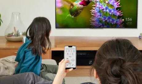 Pessoa assiste televisão com celular na mão 1