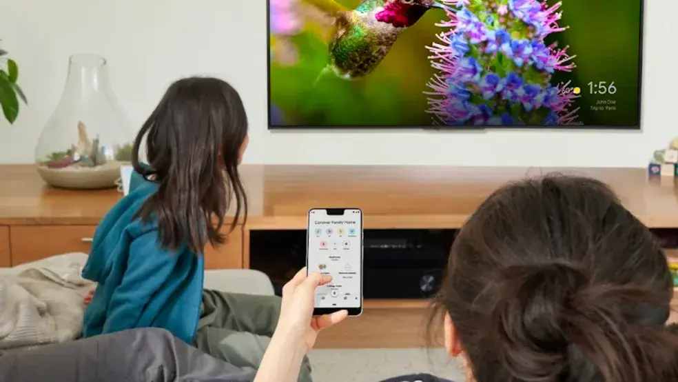 Pessoa assiste televisão com celular na mão 1