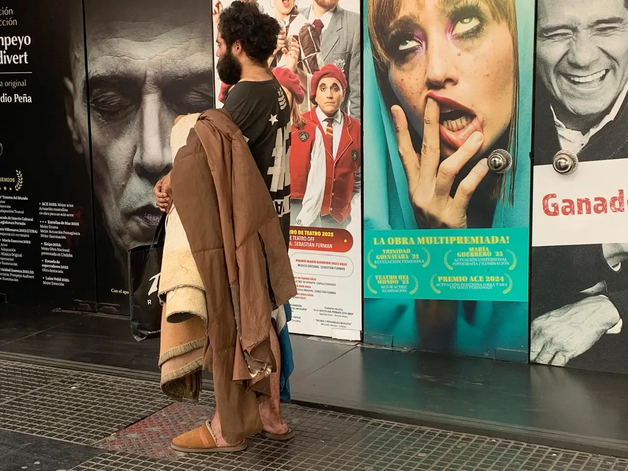 Homem em situação de rua absorto na porta de teatro