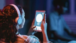 vista-traseira-da-mulher-em-casa-usando-fones-de-ouvido-e-tablet-scaled