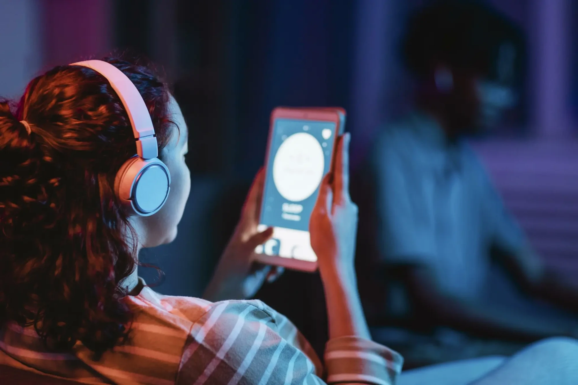 vista-traseira-da-mulher-em-casa-usando-fones-de-ouvido-e-tablet-scaled